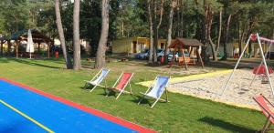 a group of lawn chairs sitting next to a playground at Firlej Plaża in Firlej