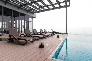 a row of chairs sitting on the edge of a swimming pool at EkoCheras Cozy Suite by DreamScape in Kuala Lumpur