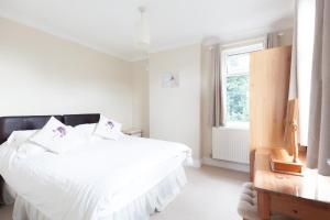 a white bedroom with a bed and a window at Toothbrush Apartments - Ipswich East - Cauldwell Ave in Ipswich