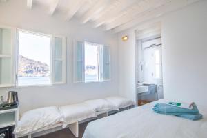a white room with two beds and two windows at On The Rocks in Symi