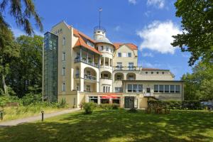 a large yellow building with a red roof at Waldschloss Parow in Ostseebad Koserow