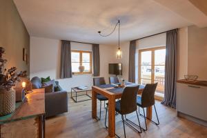 - un salon avec une table, des chaises et un canapé dans l'établissement Landhaus Herzogsteig, à Krün