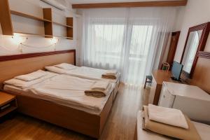 a bedroom with two beds and a desk and a window at Tisza Sport Hotel in Szeged