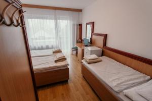 Habitación pequeña con 2 camas y espejo. en Tisza Sport Hotel, en Szeged