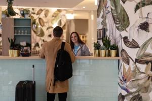 un homme debout devant un comptoir avec une femme dans l'établissement Holiday Inn - the niu, Crusoe Bremen Airport by IHG, à Brême