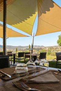 a table with wine glasses and an umbrella at Domaine Saint Esteve in Millau