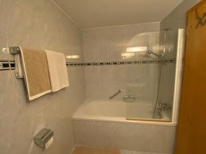 a bathroom with a tub and a shower with a towel at Studio Brunnmatt in Zermatt