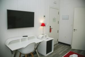 Habitación con escritorio blanco y TV en la pared. en Oh Nice Revellin Ceuta en Ceuta