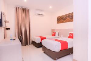 um quarto de hotel com duas camas e uma secretária em SUPER OYO Capital O 2018 Ring Road Guest House Syariah em Banda Aceh