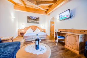a room with a bed and a table with a bottle of wine at Hotel Grundlhof in Bramberg am Wildkogel