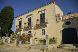 a large yellow house with balconies and flowers at Agriturismo Baglio Calanchi in Modica