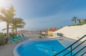 a swimming pool with chairs and the ocean in the background at Charming Villa in Funchal in Funchal