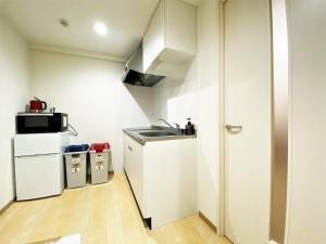 福岡市にあるランドーホテル福岡のシンクと冷蔵庫のある小さなキッチン