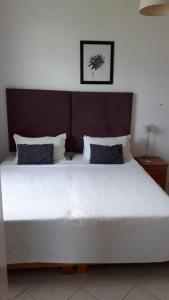 una camera da letto con un grande letto bianco con testiera in legno di Sacha Tourist Residence 2 a Mahébourg
