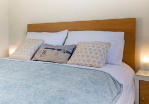 łóżko z białymi poduszkami i drewnianym zagłówkiem w obiekcie Stones Throw Studio Apartment Bude Cornwall w mieście Bude