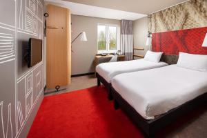 pokój hotelowy z dwoma łóżkami i telewizorem w obiekcie ibis Rugby East w mieście Crick