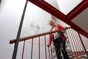 a woman standing on a staircase with a drawing on the wall at Zweizimmer-Wohnung mit Schlossblick in Chiusa