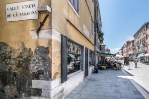 una calle en una ciudad con gente sentada fuera de una tienda en Appartamento Biennale, en Venecia