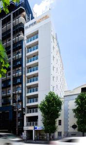 a white building with a supreme hotel sign on it at Super Hotel Namba Nipponbashi in Osaka