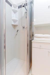 un bagno bianco con doccia e porta in vetro di Duplex Apartment in centro con posto auto privato a Ferrara