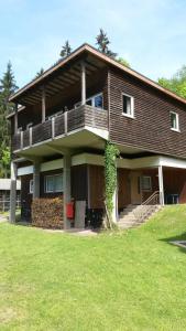 uma casa grande com uma varanda e um campo relvado em Ferienhaus Bad Hundertpfund Typ A em Großbreitenbach