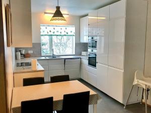 una cocina con armarios blancos y una mesa con sillas. en Apartment Tungata, en Seyðisfjörður