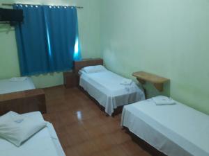 a room with three beds and a blue curtain at Hotel Chalé Ji-Parana in Ji-Paraná