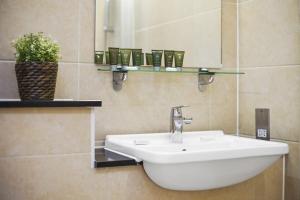 La salle de bains est pourvue d'un lavabo blanc et d'un miroir. dans l'établissement Modern Apartments in Bayswater Central London FREE WIFI & AIRCON by City Stay Aparts London, à Londres