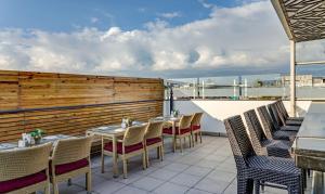 a patio with tables and chairs on a balcony at Hotel Sun Grand in Dehradun