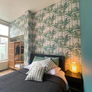 a bedroom with a bed with a palm tree wallpaper at Apartement City Centre with roof terrace and parking with additional costs in The Hague