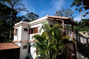 a white house with a palm tree in front of it at Casa Julia in Petrópolis