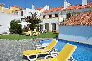 eine Terrasse mit Stühlen und einem Pool in der Unterkunft Apartamentos Cintra do Vale in Vila Nova de Milfontes