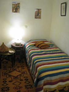 - une chambre avec un lit et une couverture rayée colorée dans l'établissement Douarskoll, à Marrakech