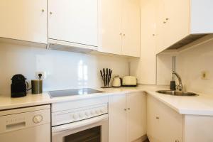 a kitchen with white cabinets and a sink at The Old Print House - Space Maison Apartments in Seville