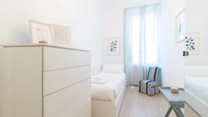 a white bedroom with a bed and a dresser at Italianway - Garigliano 8 in Milan