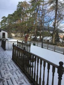 une clôture recouverte de neige avec des arbres en arrière-plan dans l'établissement Chalet, à Tyndrum