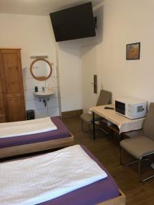 a room with two beds and a table and a microwave at Hotel Pension Schmellergarten in Munich