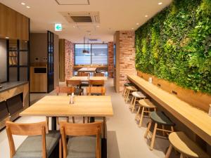a restaurant with wooden tables and a green wall at Super Hotel Shinbashi-Karasumoriguchi in Tokyo