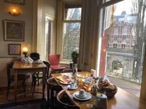 Cette chambre dispose de tables, de chaises et d'une grande fenêtre. dans l'établissement Hotel Museumzicht, à Amsterdam