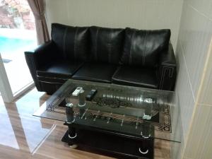 ein schwarzes Ledersofa mit einem Tisch und einer Tastatur in der Unterkunft Villa Lim in Tabanan