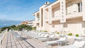 a row of white chairs on the balcony of a building at Hotel Alta La Vista in Marina di Castagneto Carducci