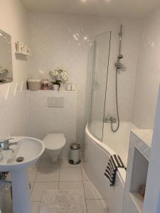 a white bathroom with a tub and a sink and a toilet at Country house in Svidník +13 photos