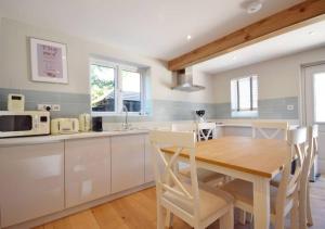 a kitchen with a wooden table and white cabinets at The Cottages at Crouchers Orchards in Chichester