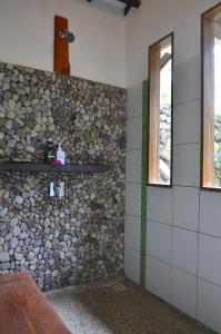 a bathroom with a stone wall and a window at Cocotinos Sekotong Lombok in Sekotong