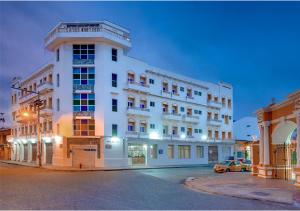 ein weißes Gebäude mit einem davor geparkt in der Unterkunft Hotel Dorado Plaza Centro Histórico in Cartagena de Indias