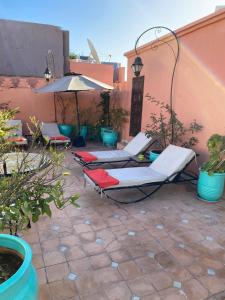 - une terrasse avec 2 chaises longues et un parasol dans l'établissement Les Jardins Mandaline, à Marrakech