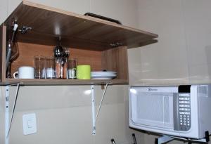 un microondas en un estante sobre un mostrador de cocina en Casa da Tereza, en Fernando de Noronha