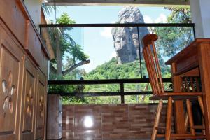 フェルナンド・デ・ノローニャにあるCasa da Terezaの大きな窓と木製の椅子が備わる客室です。
