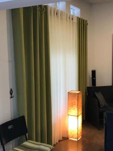 a living room with a green curtain and a lamp at Dions Guest House in Negombo