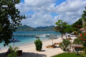 a beach with a pier and a boat in the water at Cocotinos Sekotong Lombok in Sekotong
